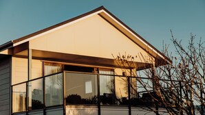 A modern house with large windows, a balcony, and a clear sky.