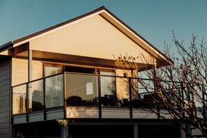 A modern house with large windows, a balcony, and a clear sky.