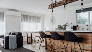 Una cocina moderna con una barra de madera, taburetes negros y luces colgantes.
