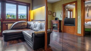 A living room with a leather sectional sofa, a fireplace, a television, and a view of mountains through large windows.