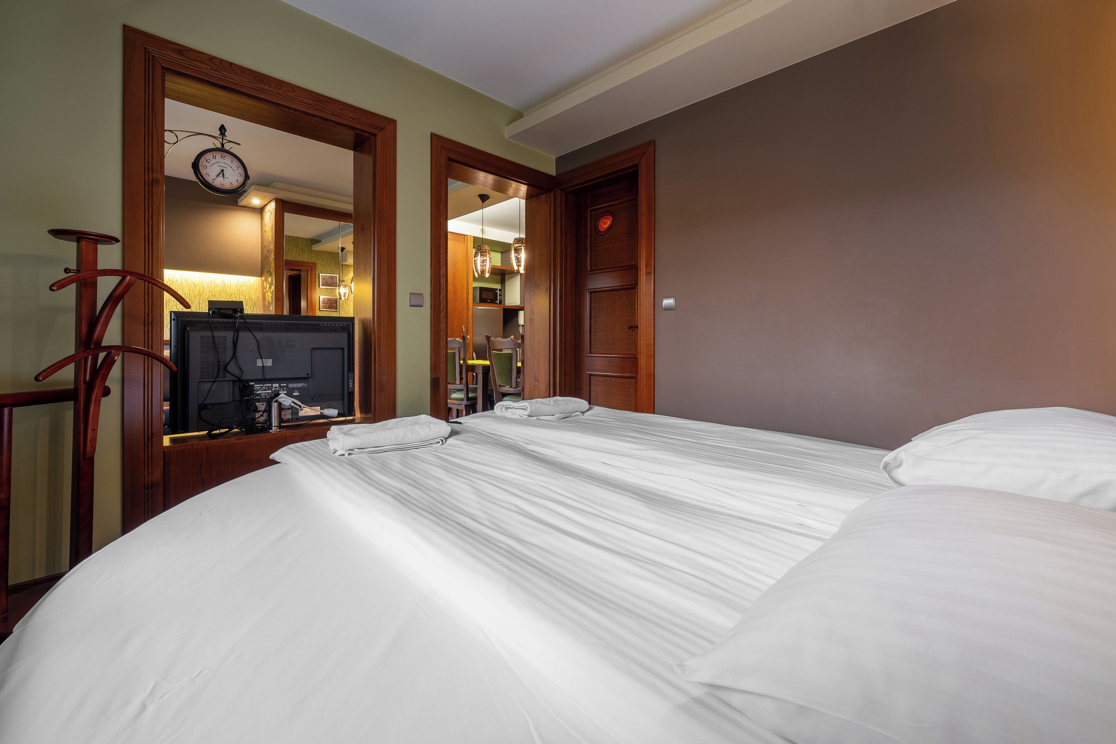 A hotel room with a large bed, a television, and a clock on the wall.