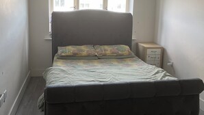 A bedroom with a bed, a nightstand, a window, and a ceiling light.