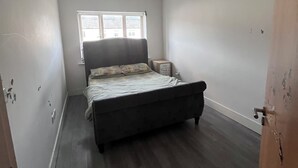A bedroom with a bed, a window, and a door.