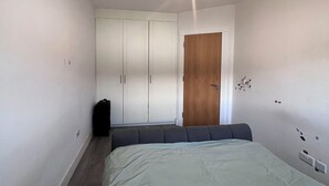 A bedroom with a bed, a wardrobe, a door, and a light fixture.