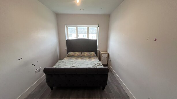 A bedroom with a bed, a window, a nightstand, and a light fixture.
