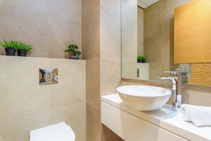 A modern bathroom with a white sink, a mirror, and two potted plants on the wall. - Viva 3-BR Apt in Waterfront Dbayeh (Dbayeh)