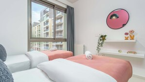 A modern hotel room with two beds, a large window, a round mirror, and a shelf with decorative items. - Viva 3-BR Apt in Waterfront Dbayeh (Dbayeh)