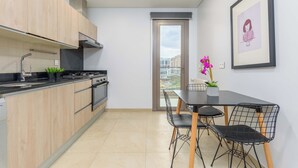 A modern kitchen with wooden cabinets, a black countertop, and a dining area with a table and chairs. - Viva 3-BR Apt in Waterfront Dbayeh (Dbayeh)
