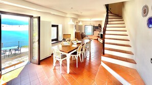 Un vaste espace de vie comprenant une table à manger, des chaises, un escalier et une vue sur la mer.