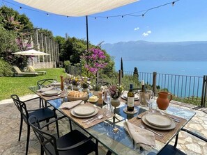 A dining table set outdoors with a view of a lake and mountains.