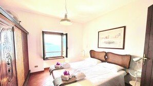 Une chambre d’hôtel avec un lit, une fenêtre donnant sur un paysage agréable, une porte et un tableau encadré au mur.