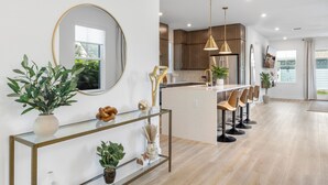 Een moderne keuken met een centraal eiland, barstoelen en hanglampen.