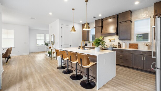 Een moderne keuken met een centraal eiland, barstoelen en hanglampen.