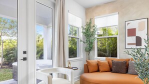 Een moderne woonkamer met een gebogen oranje bank, een witte fauteuil en een klein bijzettafeltje.
