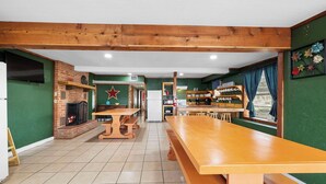 A spacious room with a long wooden table, a brick fireplace, and a star decoration on the wall. - Big Oak@ FrioRiverVacationRentals (Concan)