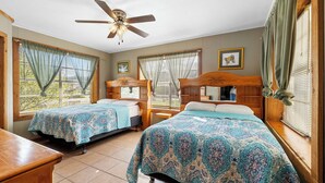 A room with two wooden beds, a ceiling fan, and large windows with curtains. - Big Oak@ FrioRiverVacationRentals (Concan)