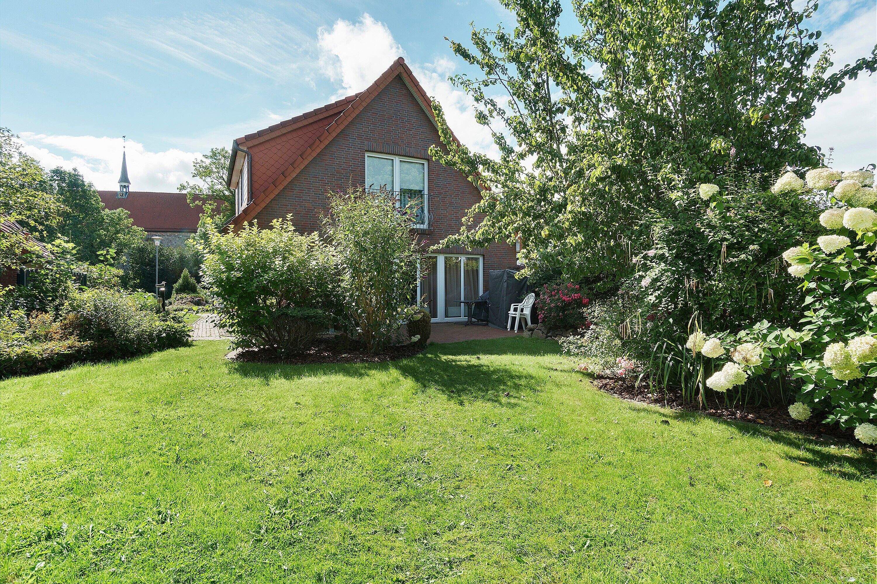 A house with a red roof, a brick exterior, and a well-maintained lawn.