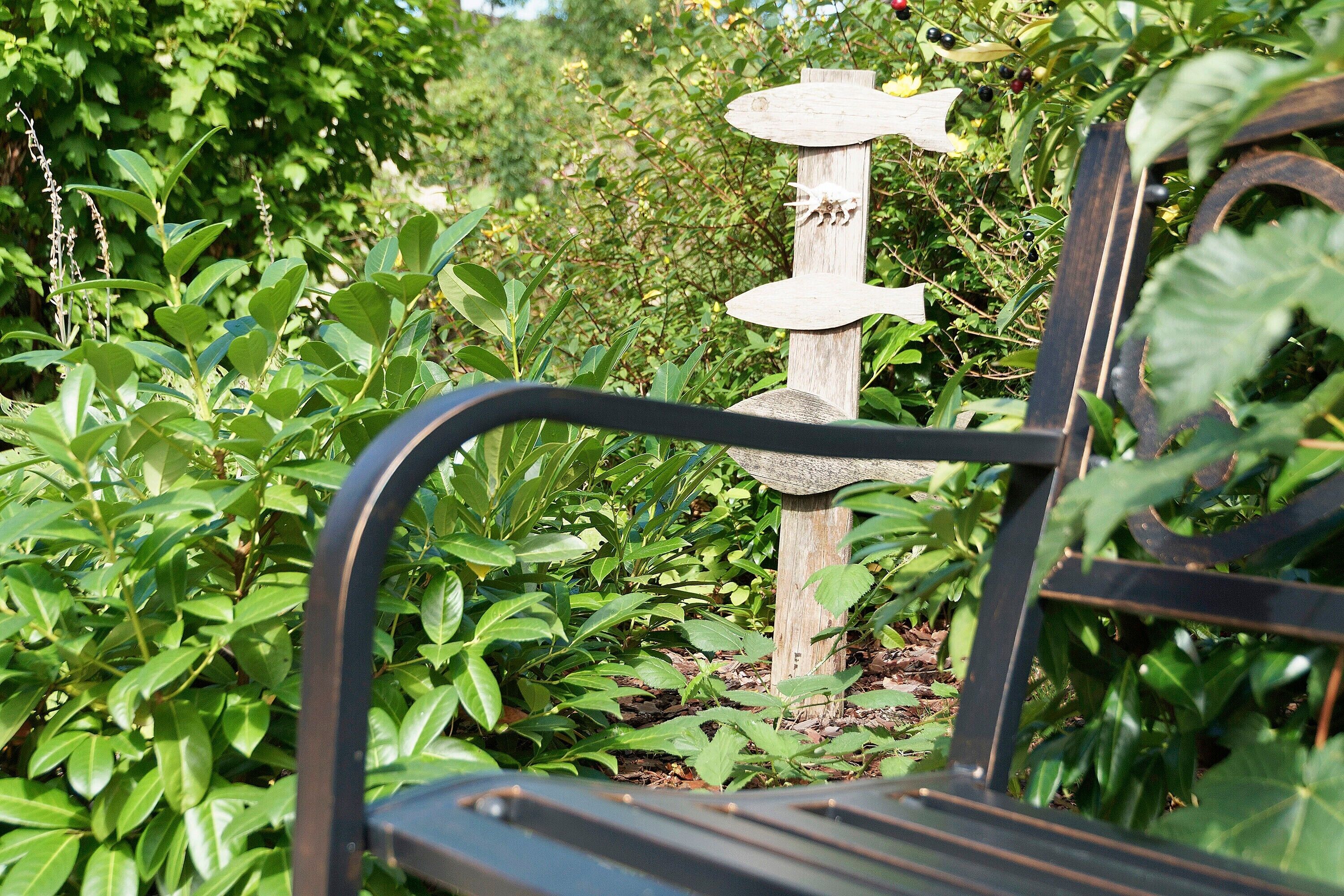 A bench with a wooden post and directional sign in a garden.