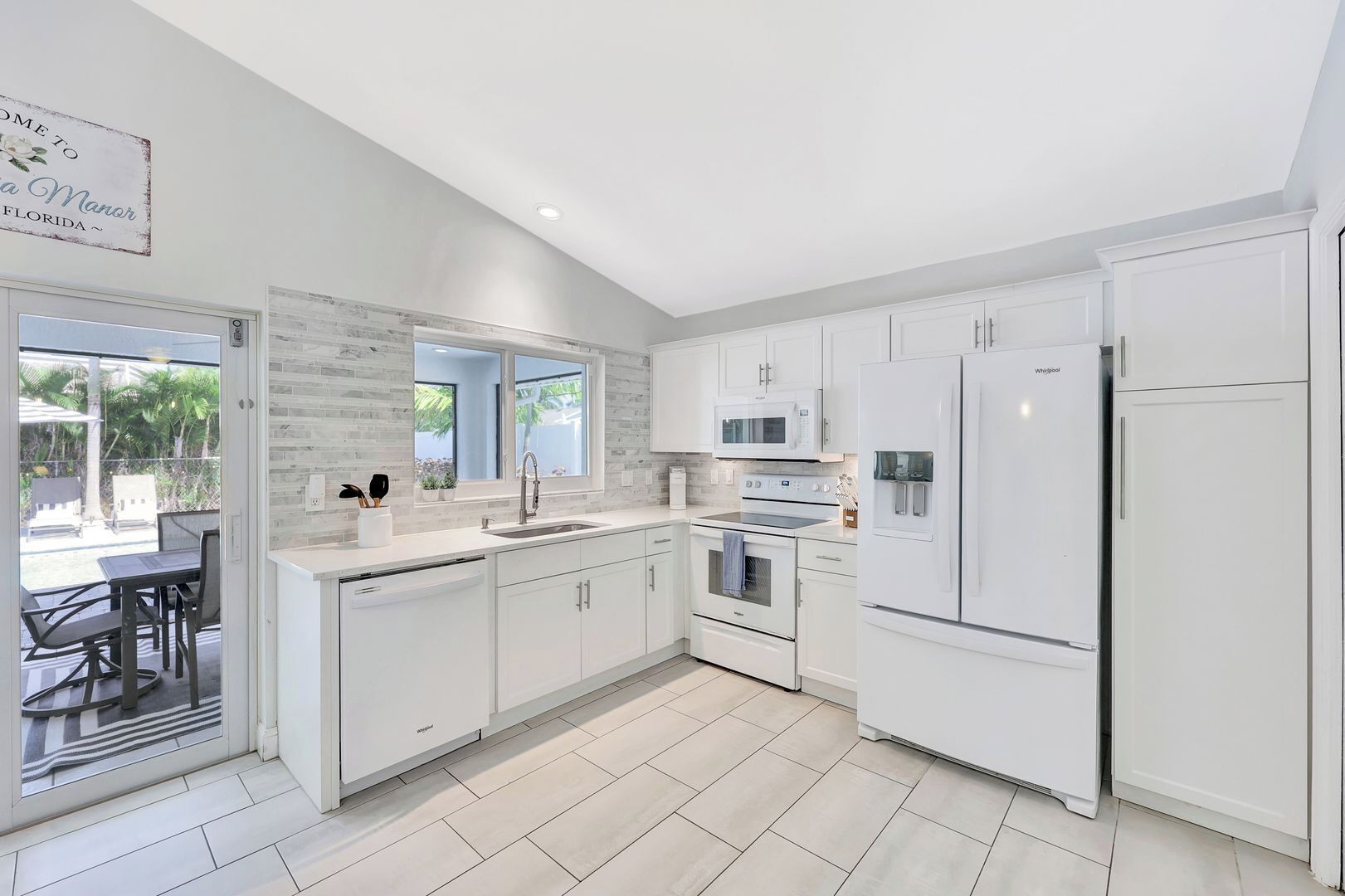 A modern kitchen with white cabinetry, a built-in oven, microwave, and refrigerator.