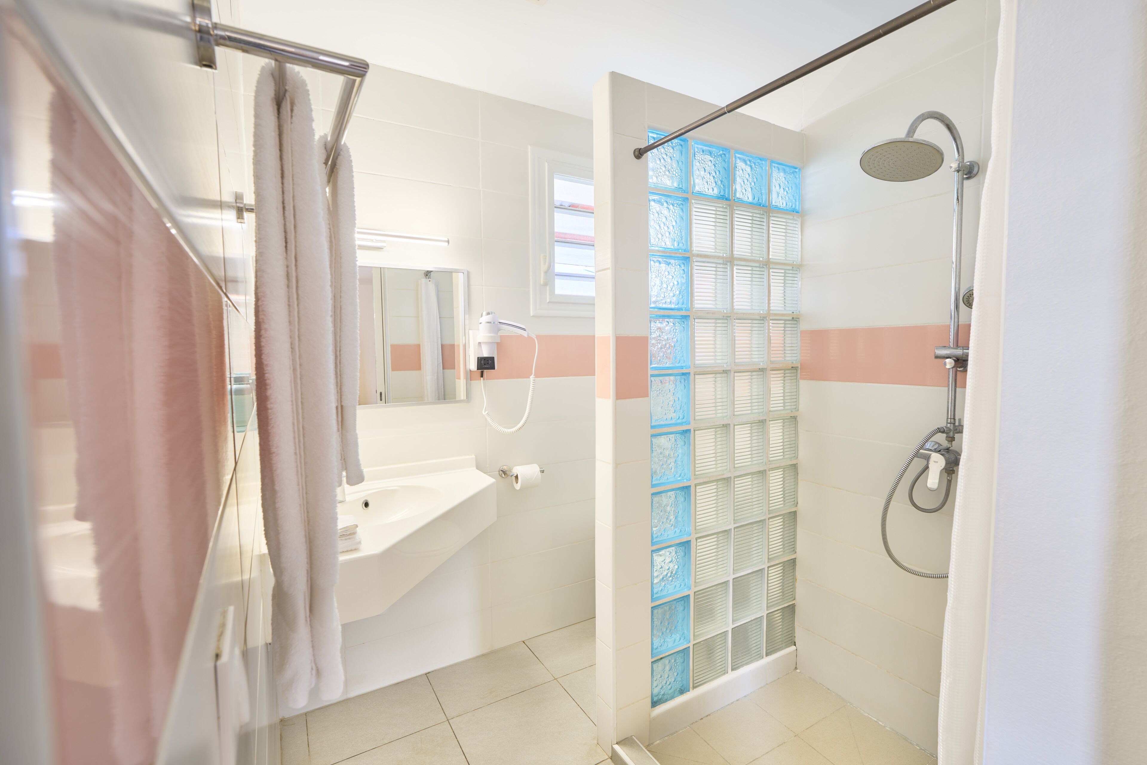 A bathroom with a glass shower enclosure, a sink, and a mirror.