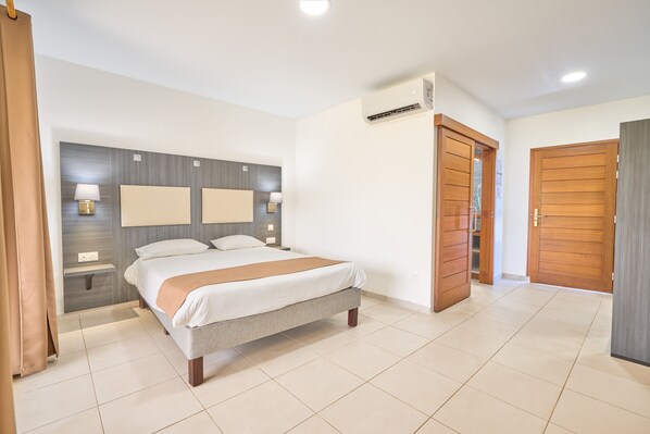 Una habitación de hotel con cama, mesitas de noche, armario y aire acondicionado.