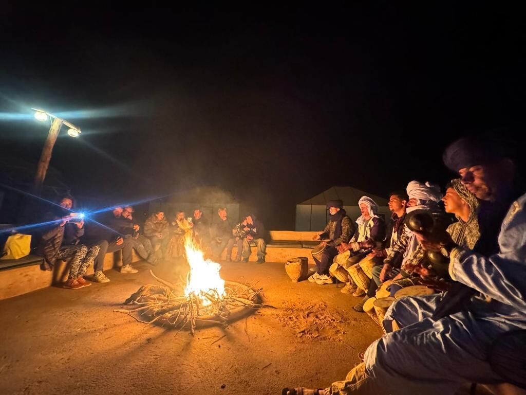 Un grupo de personas reunidas alrededor de una fogata por la noche.