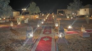 A carpeted pathway leading to a building with lanterns and a sign reading "HABITAT". - Ksar Merzouga  (Taouz)