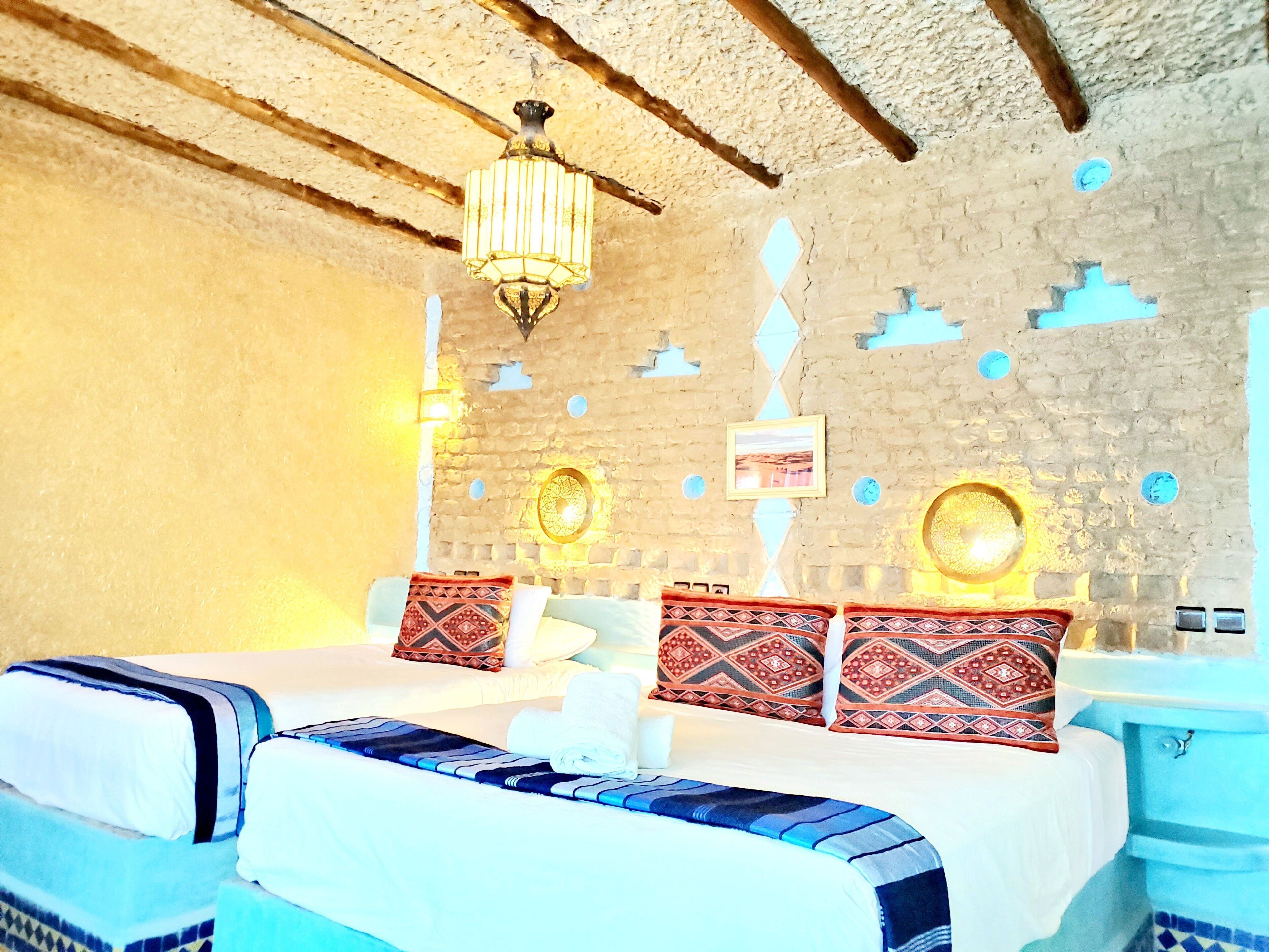 Una habitación con dos camas, una araña y elementos decorativos en las paredes.