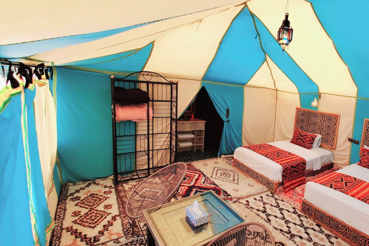 A tent with two beds, a small table, and a hanging lantern.