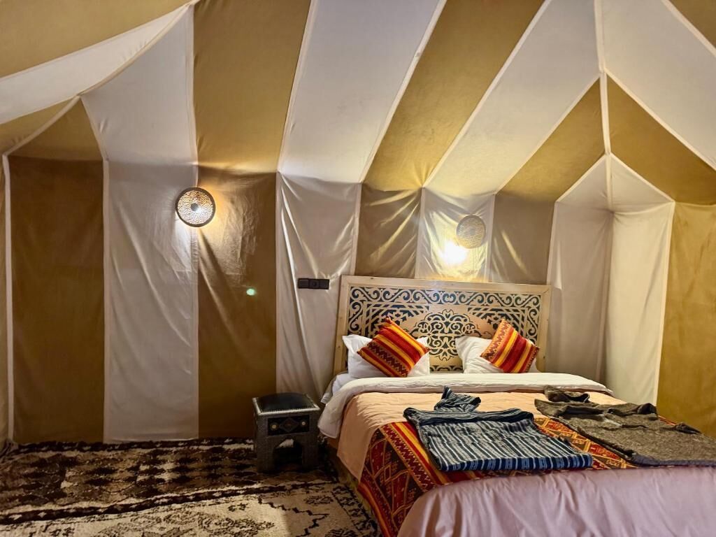 A tent-style room with a bed, pillows, and a nightstand.