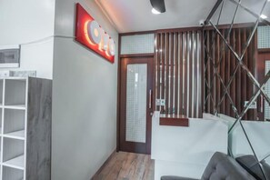 Un'area reception dal design moderno, con scrivania, angolo salotto e una parete divisoria in legno.