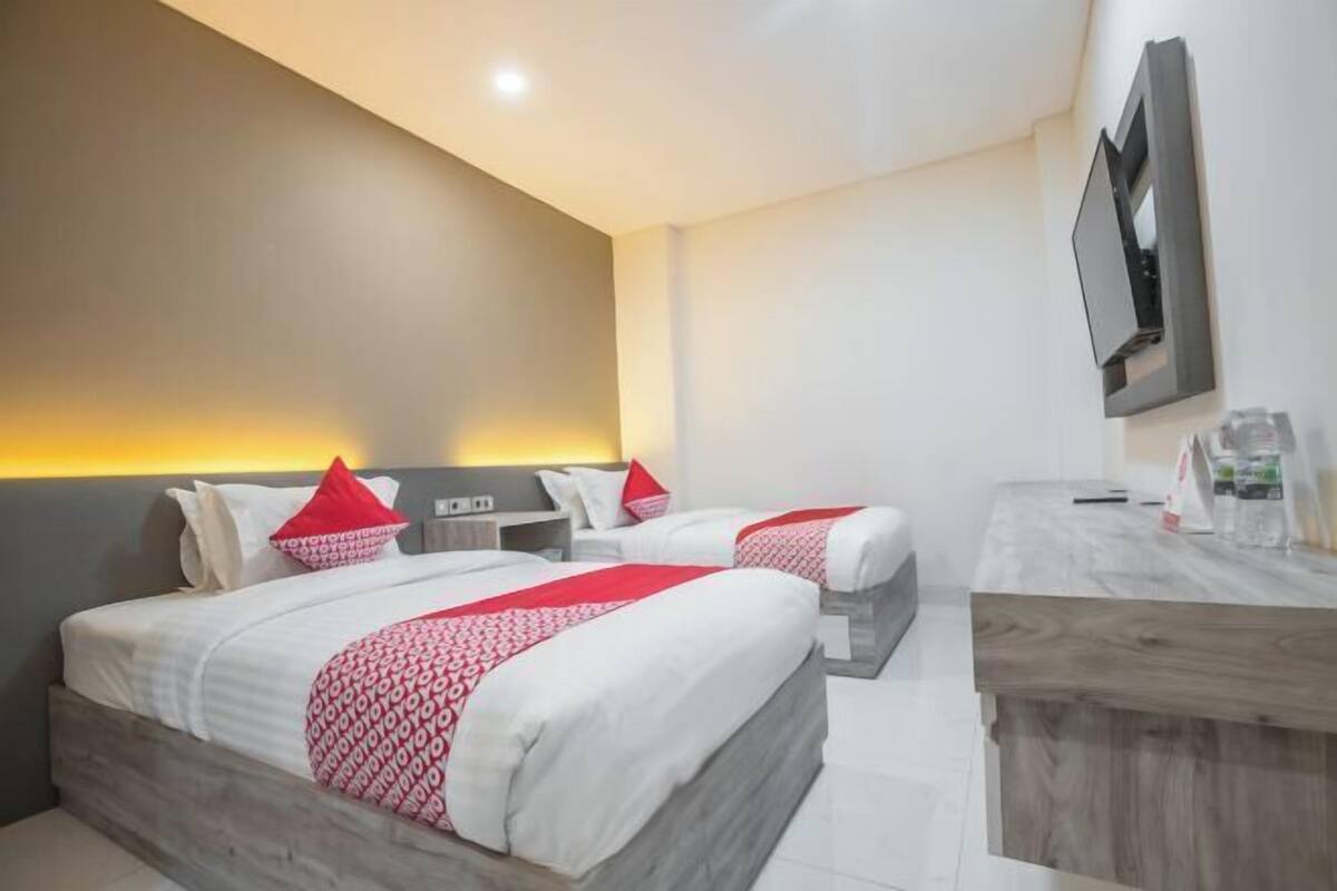 Una habitación de hotel con dos camas, un escritorio, un televisor y un minibar.