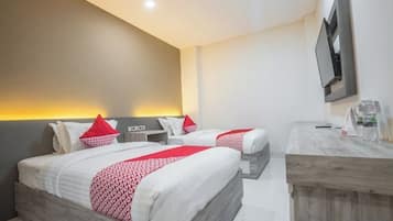 A hotel room with two beds, a desk, and a TV.