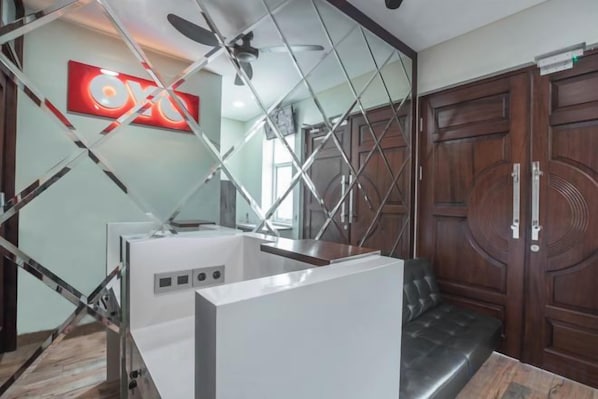 A room with a ceiling fan, a wooden wardrobe, and a modern kitchen area with appliances.