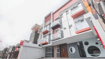 A multi-story building with a flat roof, a gated entrance, and a visible door.
