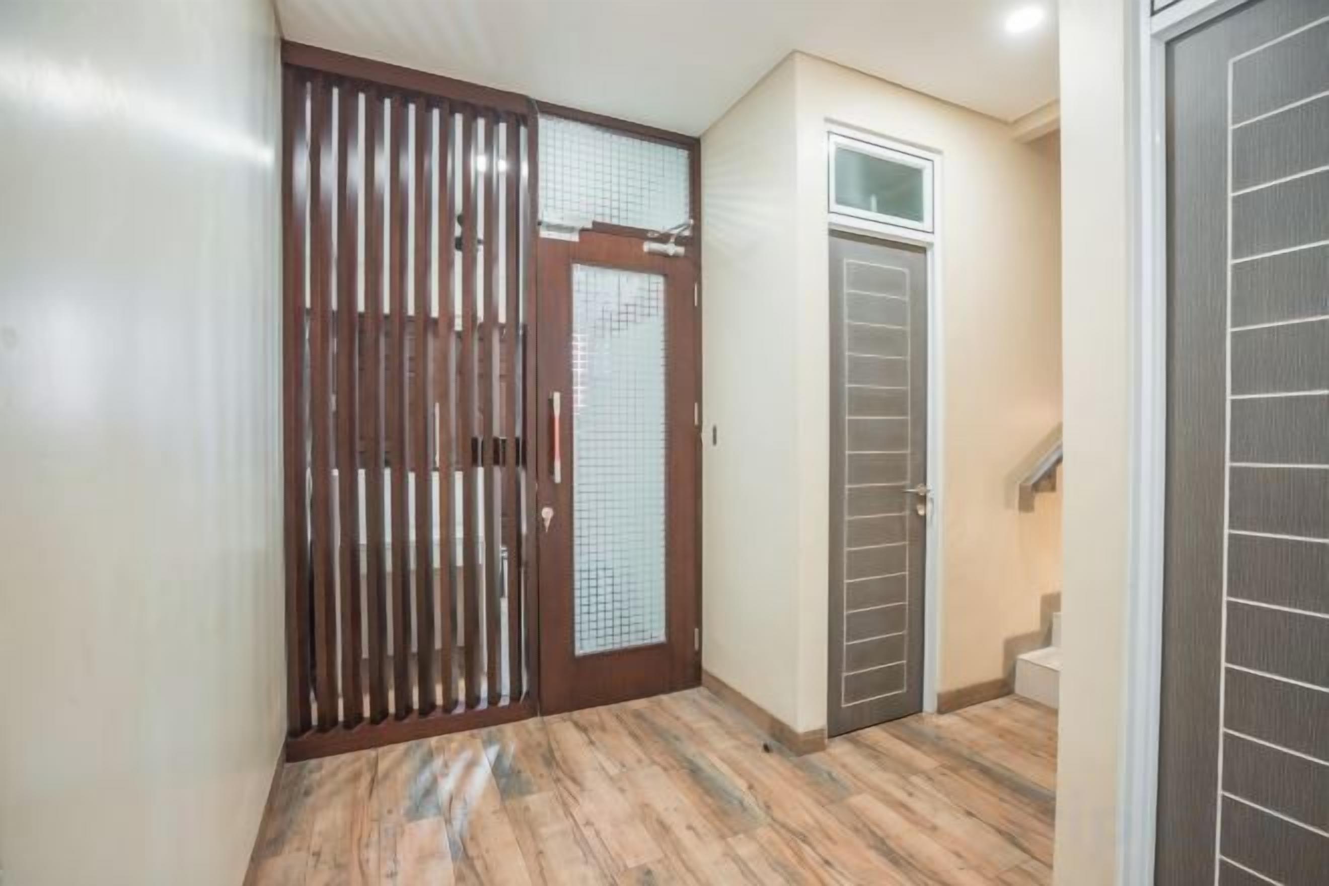 Um corredor com uma porta de madeira, uma porta de vidro e uma escada que leva a um andar superior.