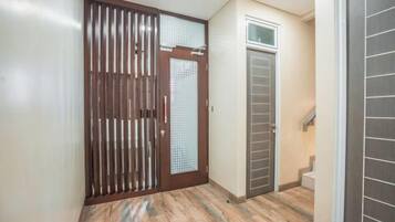 Um corredor com uma porta de madeira, uma porta de vidro e uma escada que leva a um andar superior.