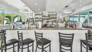 Un área de bar moderna con mostrador, taburetes y estantes llenos de botellas.