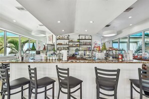 A modern bar area with a counter, bar stools, and shelves stocked with bottles.