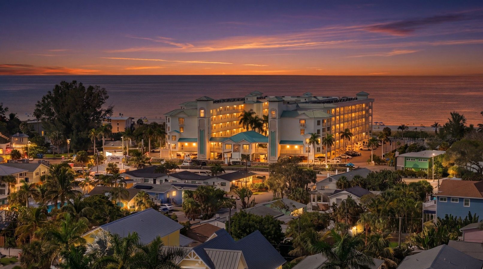 A hotel with multiple buildings, a beachfront view, and a well-lit facade.
