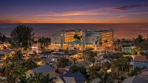 Un hôtel composé de plusieurs bâtiments, offrant une vue sur la plage et doté d’une façade bien éclairée.
