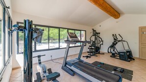 A gym with a treadmill, stationary bike, and weight machine. - Holiday Home 'Gite Fontenelle Alpilles' with Shared Pool, Wi-Fi & Air Conditioning (Arles)