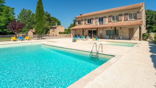 A two-story building with a swimming pool, outdoor seating, and a clear blue sky. - Holiday Home 'Gite Fontenelle Alpilles' with Shared Pool, Wi-Fi & Air Conditioning (Arles)