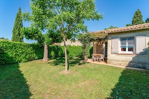 A house with a garden, a patio with a table and chairs, and a stone wall. - Holiday Home 'Gite Fontenelle Alpilles' with Shared Pool, Wi-Fi & Air Conditioning (Arles)