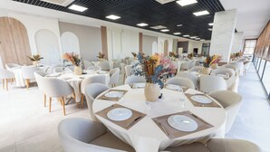 A spacious dining area with round tables set for four, each with white plates, cutlery, and decorative vases. - Tek Hotel Murefte (Şarköy)