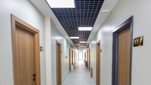 A long, narrow hallway with wooden doors on both sides, white walls, and a tiled floor. - Tek Hotel Murefte (Şarköy)