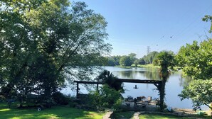 Eine ruhige Seenlandschaft mit einer hölzernen Pergola, einem gepflasterten Weg und Picknicktischen.