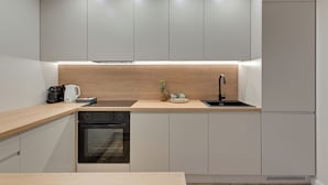 A modern kitchen with a wooden countertop, built-in oven, and a sink. - Seaside Latarników by Downtown Apartments (Gdańsk)