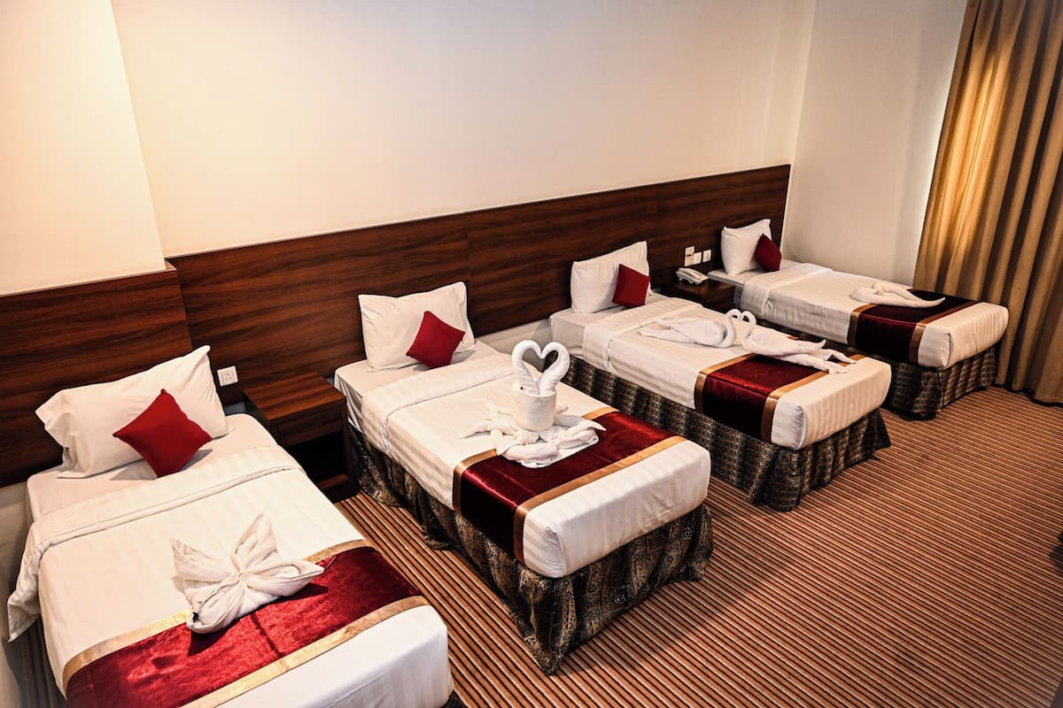 A hotel room with four beds, each with white bedding and red pillows.