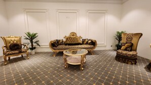 A room with a patterned floor, a tufted sofa, two ornate chairs, and a glass coffee table. - ABRAJ ALMISK HOTEL (Makkah)